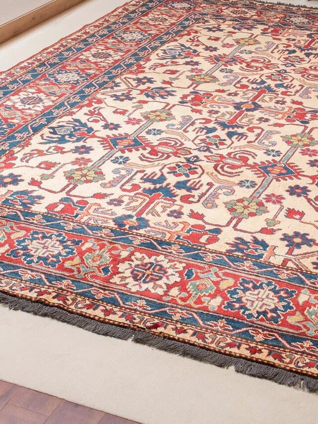 Teppich mit hellem Feld, rot-blauen Ranken und breiter rot-blauer Bordüre mit dunklen Fransen