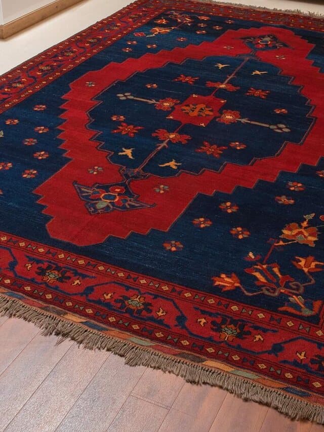 Teppich mit dunkelblauem Feld, großem rotem gestuftem Medaillon und roter Bordüre